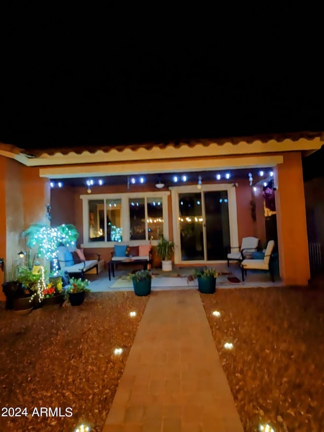 back of house at twilight featuring a patio area