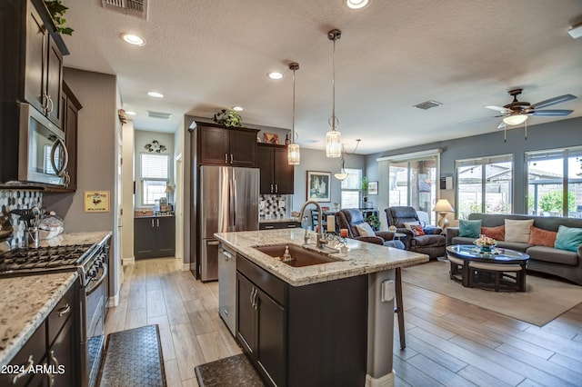 kitchen featuring dark brown cabinetry, plenty of natural light, appliances with stainless steel finishes, and a sink