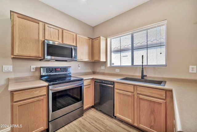 kitchen featuring stainless steel appliances, light brown cabinets, sink, and light wood-type flooring