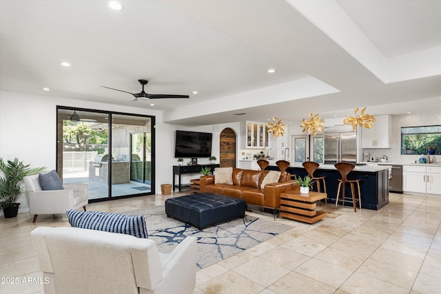 living room with ceiling fan, sink, and a wealth of natural light