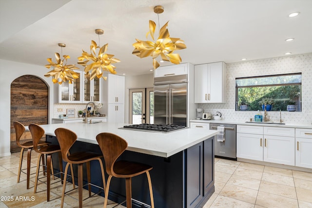 kitchen with hanging light fixtures, stainless steel appliances, and a kitchen island with sink