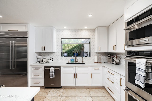 kitchen with sink, stainless steel appliances, light tile patterned floors, tasteful backsplash, and white cabinets