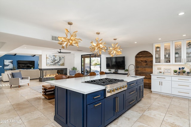 kitchen featuring blue cabinetry, sink, stainless steel gas cooktop, pendant lighting, and white cabinets