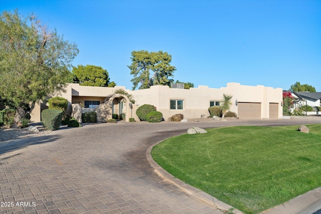 pueblo-style house with a front yard and a garage