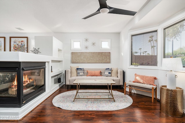 living room with built in shelves, ceiling fan, and dark hardwood / wood-style floors