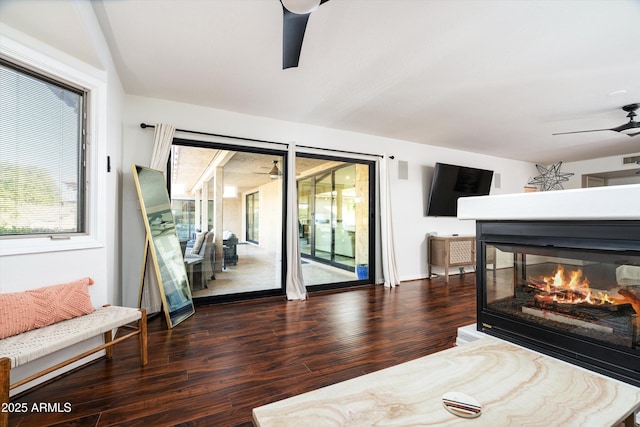 bedroom with a multi sided fireplace, ceiling fan, dark hardwood / wood-style flooring, and access to exterior