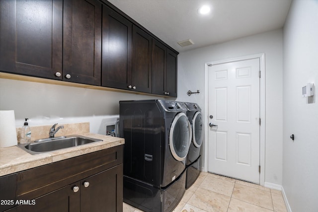 washroom with cabinets, washing machine and dryer, light tile patterned floors, and sink