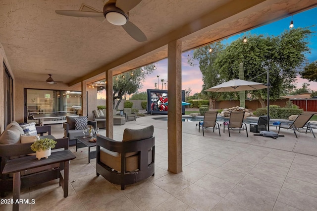 patio terrace at dusk with outdoor lounge area and ceiling fan