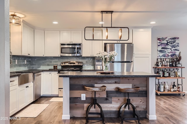 1718 W Voltaire Ave, Phoenix, AZ 85029 - kitchen with appliances with stainless steel finishes, dark countertops, wood finished floors, decorative backsplash, and white cabinetry