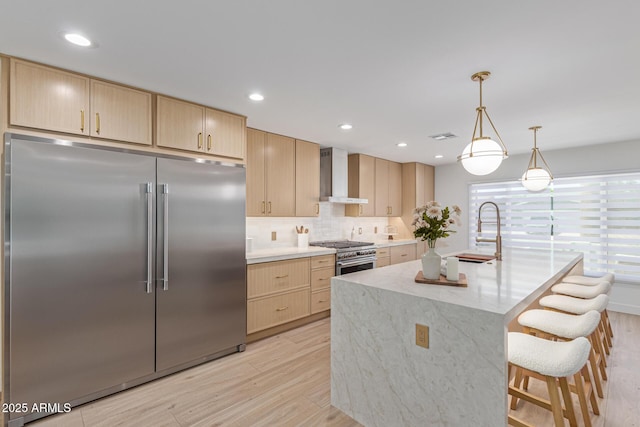 8119 E San Miguel Ave, Scottsdale, AZ 85250 - kitchen with high quality appliances, wall chimney exhaust hood, light brown cabinets, light wood finished floors, and backsplash