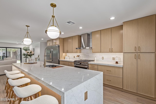 8119 E San Miguel Ave, Scottsdale, AZ 85250 - kitchen featuring wall chimney exhaust hood, premium appliances, a kitchen breakfast bar, light wood-style flooring, and light stone counters