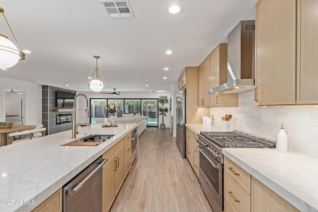 8119 E San Miguel Ave, Scottsdale, AZ 85250 - kitchen with appliances with stainless steel finishes, light brown cabinets, wall chimney range hood, ceiling fan, and light wood-style floors