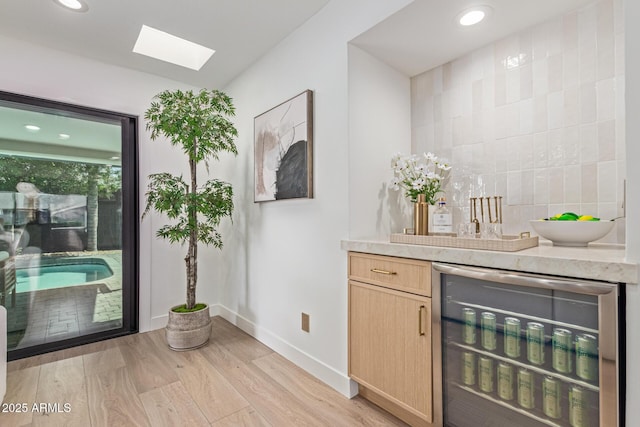 8119 E San Miguel Ave, Scottsdale, AZ 85250 - bar featuring beverage cooler, light wood-style floors, a skylight, recessed lighting, and decorative backsplash