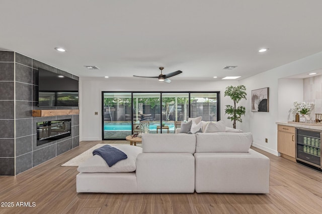 8119 E San Miguel Ave, Scottsdale, AZ 85250 - living area featuring a tiled fireplace, wine cooler, light wood-style floors, and recessed lighting