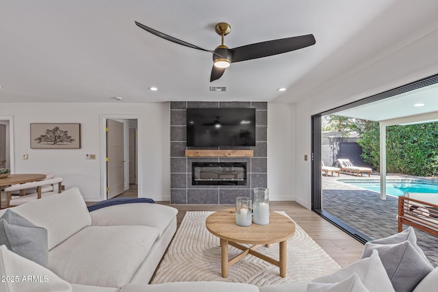 8119 E San Miguel Ave, Scottsdale, AZ 85250 - living room featuring a ceiling fan, light wood finished floors, a tiled fireplace, and recessed lighting