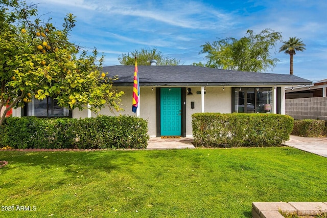 view of front of home featuring stucco siding, a front lawn, and roof with shingles