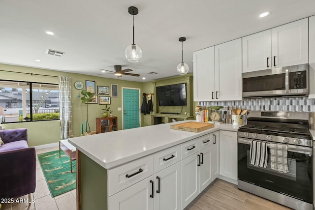 kitchen featuring visible vents, a peninsula, stainless steel appliances, light countertops, and open floor plan