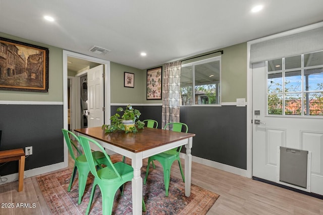 dining area with light wood-style floors, visible vents, stacked washer and dryer, and a healthy amount of sunlight
