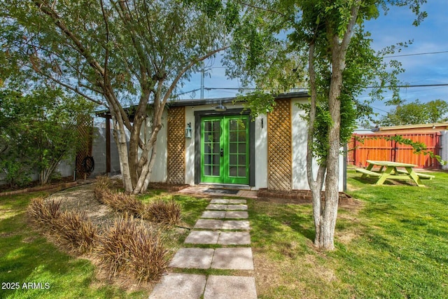 property entrance featuring french doors, a yard, and fence