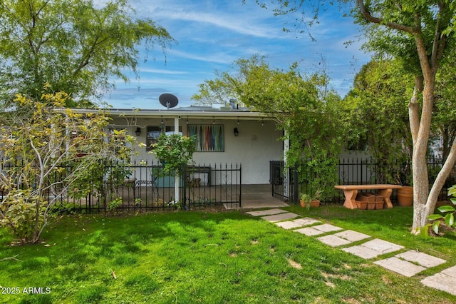 back of house featuring a fenced front yard, stucco siding, and a yard