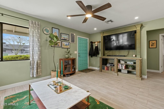 living area featuring visible vents, wood finished floors, baseboards, and ceiling fan
