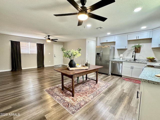 kitchen with appliances with stainless steel finishes, ceiling fan, sink, wood-type flooring, and white cabinets