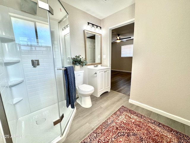 bathroom with ceiling fan, hardwood / wood-style floors, an enclosed shower, toilet, and vanity