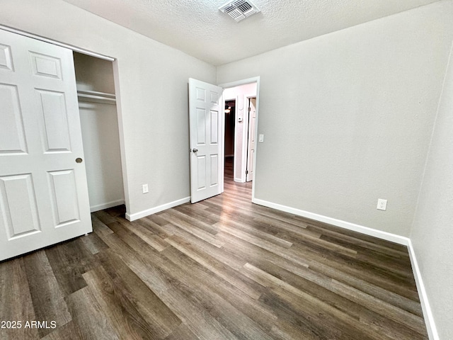 unfurnished bedroom featuring dark hardwood / wood-style flooring, a textured ceiling, and a closet