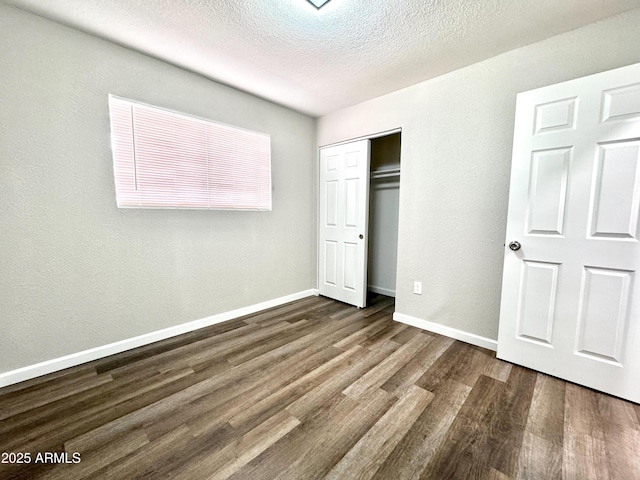 unfurnished bedroom with a textured ceiling, a closet, and dark wood-type flooring