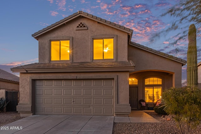 mediterranean / spanish home featuring a tile roof, concrete driveway, stucco siding, and an attached garage