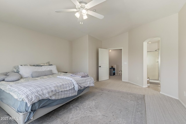 bedroom featuring lofted ceiling, baseboards, arched walkways, ceiling fan, and light carpet