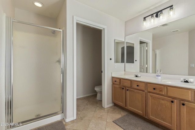 bathroom featuring toilet, double vanity, a sink, and a shower stall