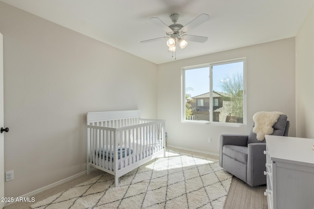 bedroom featuring a crib, baseboards, and ceiling fan