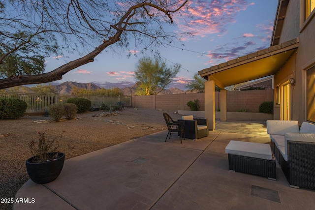 patio terrace at dusk with a mountain view and a fenced backyard