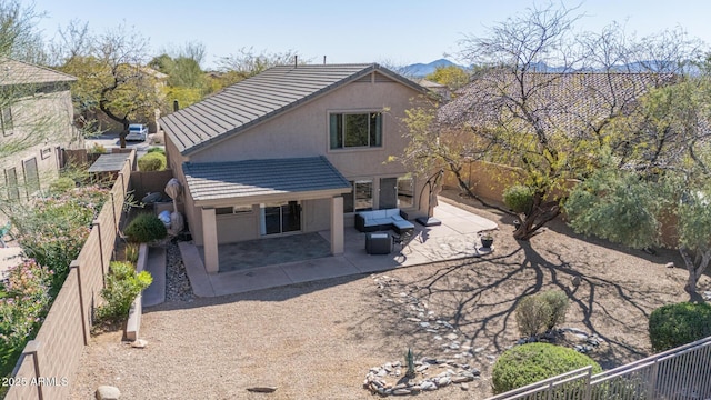 back of house with stucco siding, a tile roof, a fenced backyard, and a patio