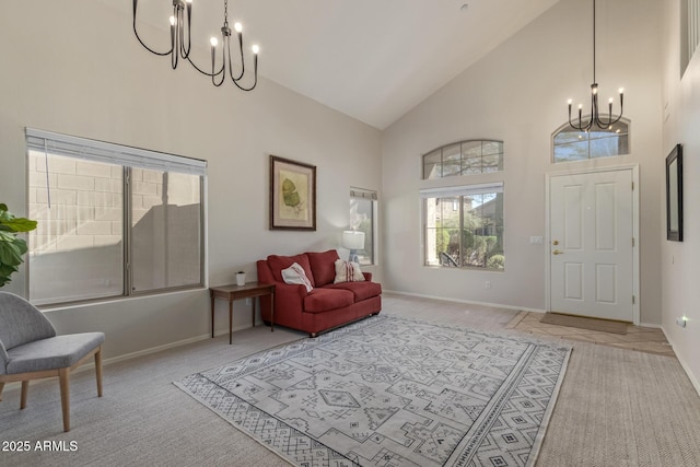 interior space with an inviting chandelier, light carpet, high vaulted ceiling, and baseboards