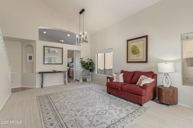 living room featuring high vaulted ceiling, carpet floors, a chandelier, baseboards, and arched walkways