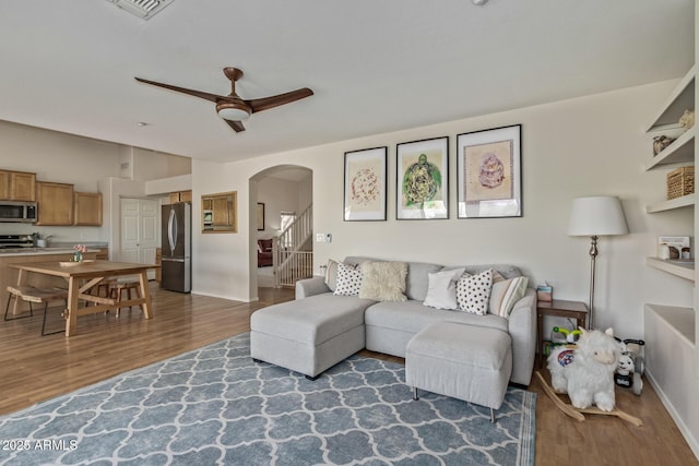 living area featuring visible vents, ceiling fan, wood finished floors, arched walkways, and vaulted ceiling