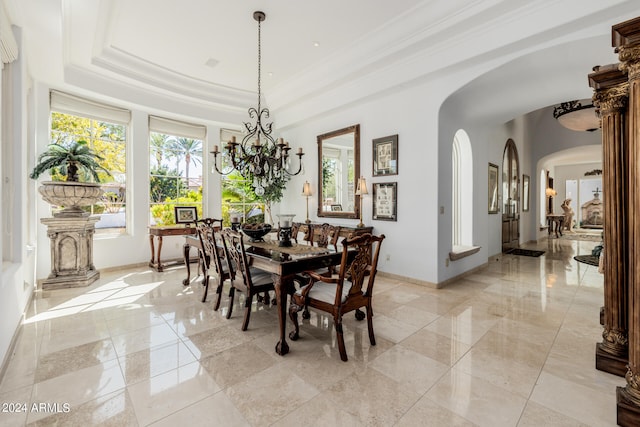 dining room featuring a raised ceiling, ornamental molding, and a notable chandelier