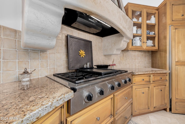 kitchen with light stone counters, stainless steel gas stovetop, light tile patterned floors, and backsplash