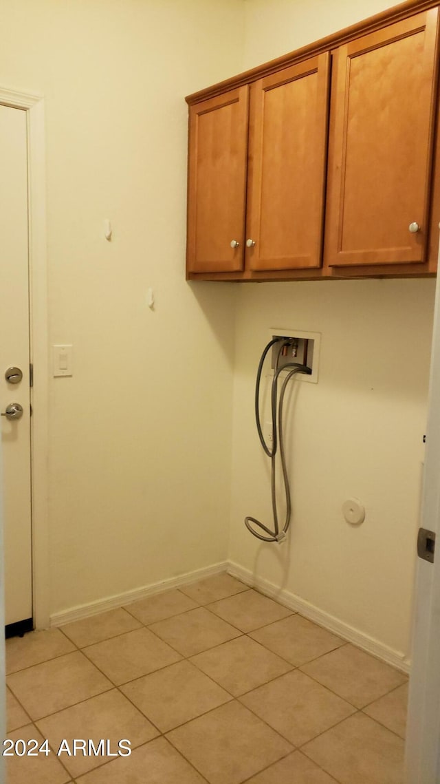 laundry area featuring washer hookup, light tile patterned floors, and cabinets