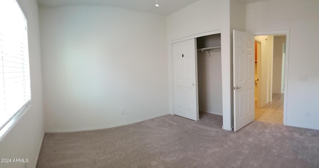 unfurnished bedroom featuring light colored carpet and a closet