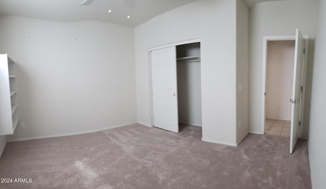 unfurnished bedroom featuring a closet, ceiling fan, and light colored carpet