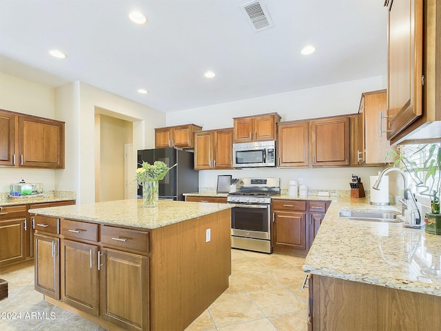 kitchen featuring sink, a kitchen island, stainless steel appliances, light tile patterned floors, and light stone countertops