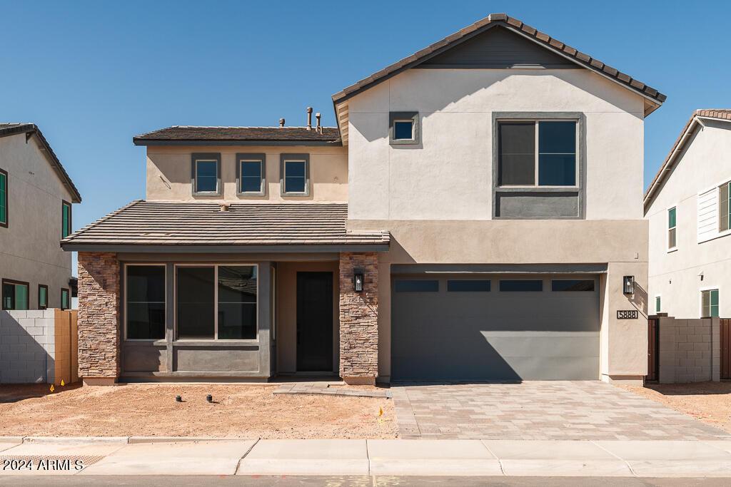 view of front facade featuring decorative driveway, fence, an attached garage, and stucco siding