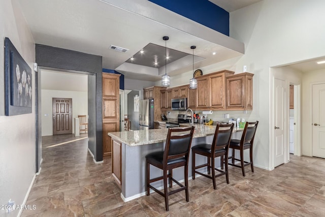 kitchen featuring pendant lighting, a kitchen breakfast bar, light stone countertops, appliances with stainless steel finishes, and kitchen peninsula