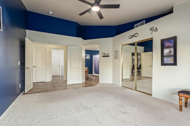 unfurnished bedroom with carpet flooring, ceiling fan, a closet, and high vaulted ceiling