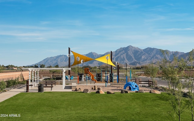 community playground with a mountain view and a yard
