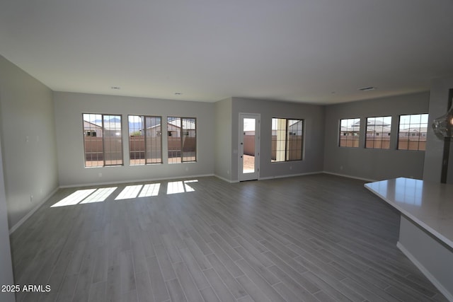 unfurnished living room featuring dark wood-type flooring, visible vents, and baseboards
