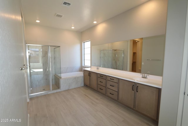 bathroom with a stall shower, a sink, a bath, visible vents, and double vanity